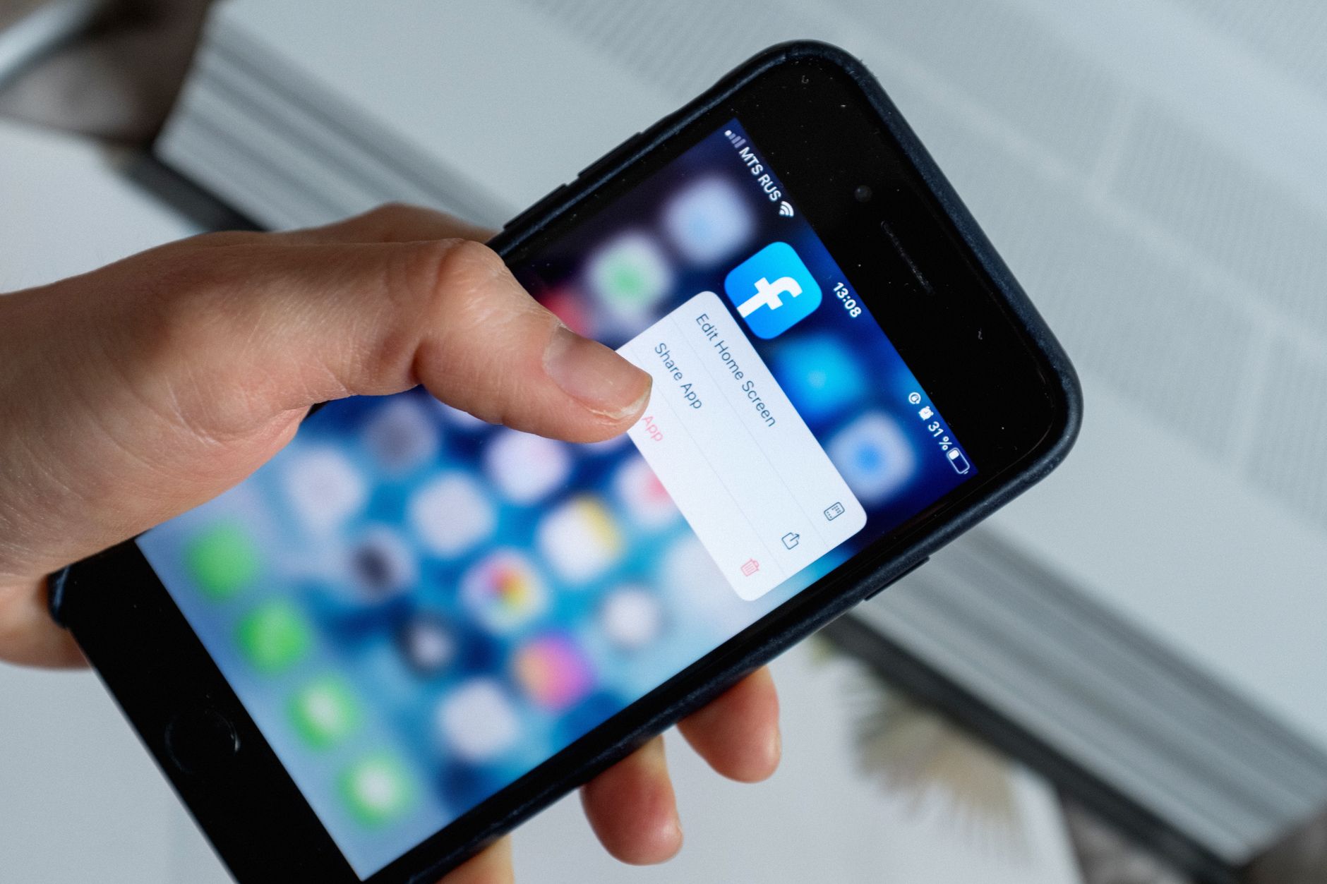 Comment Facebook collecte vos informations personnelles, sur et en dehors de la plateforme — personne utilisant l'application Facebook sur smartphone